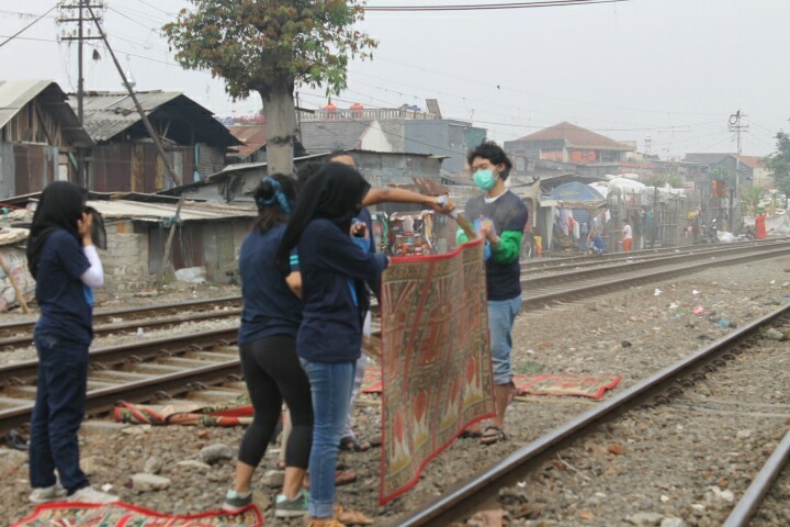 MENEGANGKAN: Panitia baksos Himastron membersihkan sajadah di sekitar rel kereta api, Desa Ciroyom